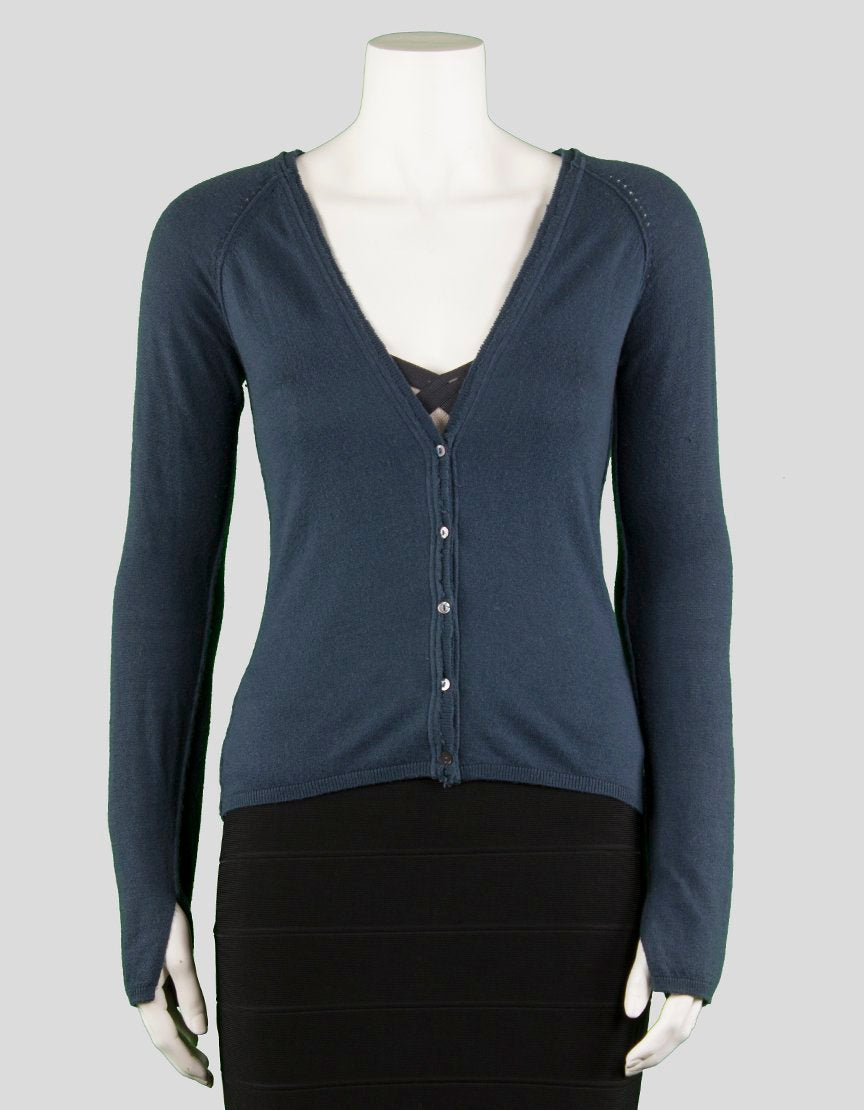 A blue long sleeve cardigan with a v-neck and button down front, displayed on a mannequin. The cardigan has distressed edges and a slit at the sleeve cuff.