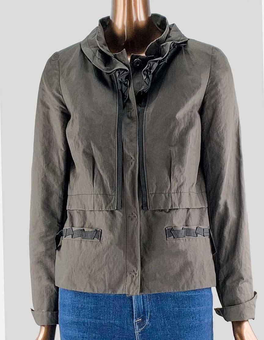 A brown Tahari women's blazer with black grosgrain trim, front snap closure, and two front slit pockets. It features a standing collar, seam detail at the mid-point, and foldover cuffs.