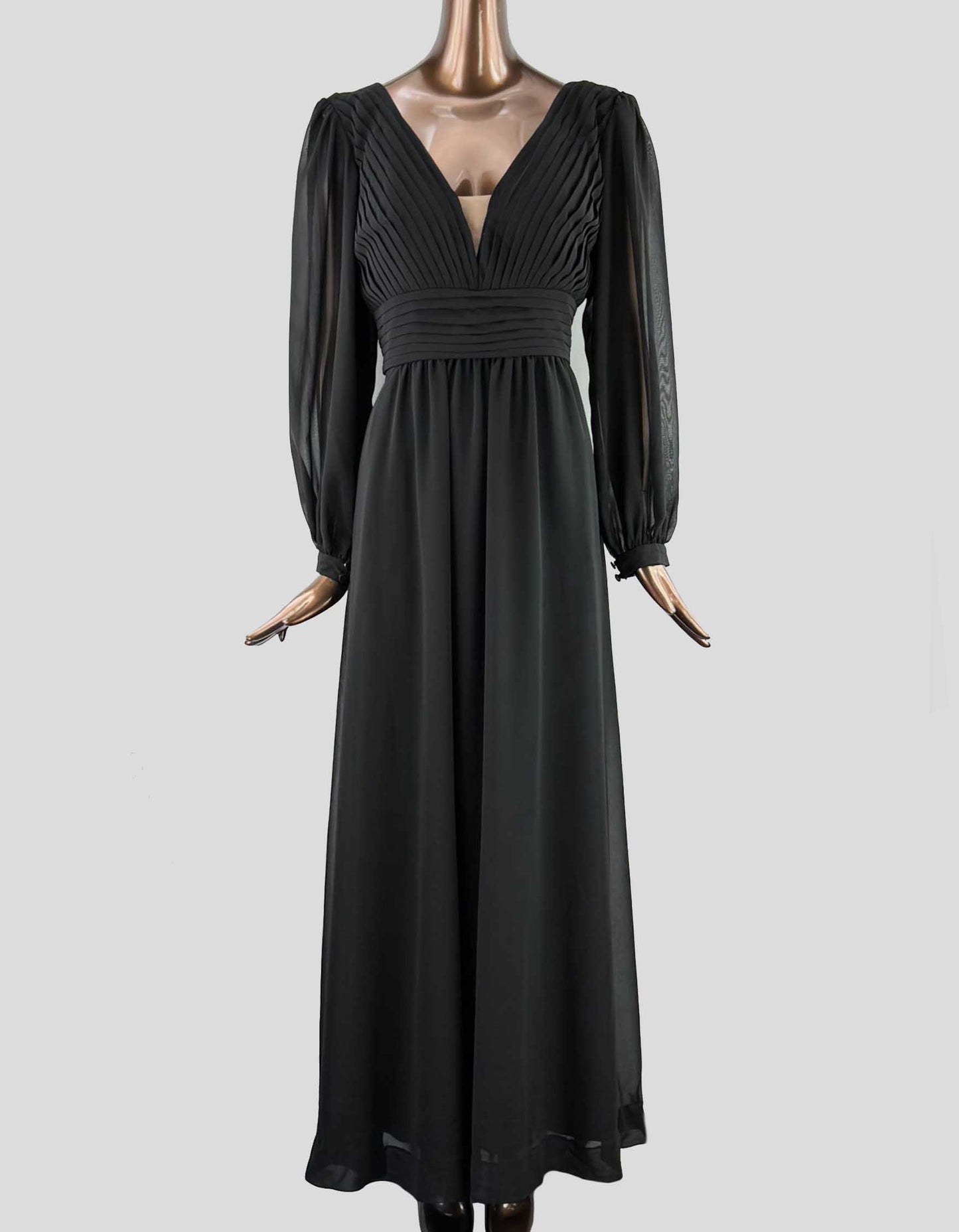 A long black dress with sheer sleeves, a V-neck, and pleated details at the bust and waist, displayed on a mannequin.