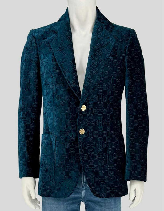 Authentic screen-worn GUCCI teal velvet blazer with signature interlocking GG monogram pattern. Features gold-tone button closures and luxurious velvet construction with 100% viscose lining. 