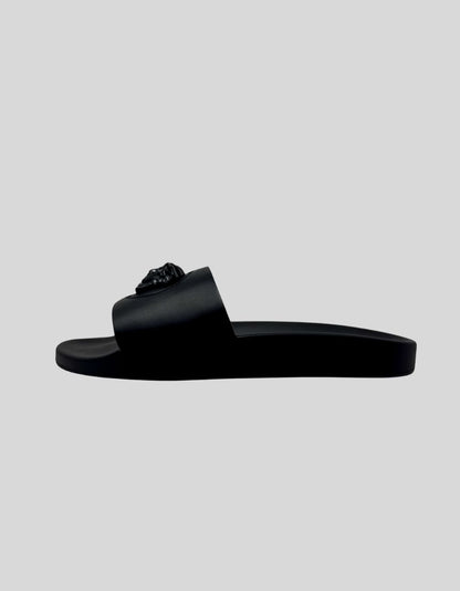 VERSACE Palazzo Medusa Pool Slide Sandals in Black. Iconic three-dimensional Medusa plaque at center. Surrounded by signature Greca pattern accent. All-black rubber construction. Molded footbed with Medusa head logo. Slip-on style.