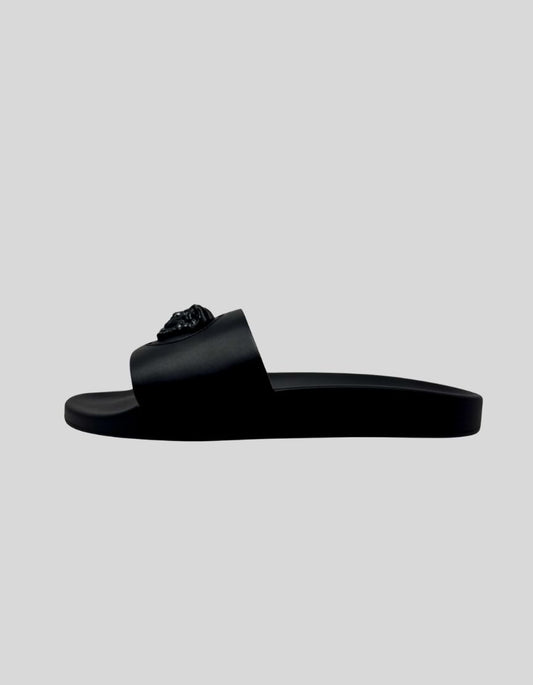 VERSACE Palazzo Medusa Pool Slide Sandals in Black. Iconic three-dimensional Medusa plaque at center. Surrounded by signature Greca pattern accent. All-black rubber construction. Molded footbed with Medusa head logo. Slip-on style.