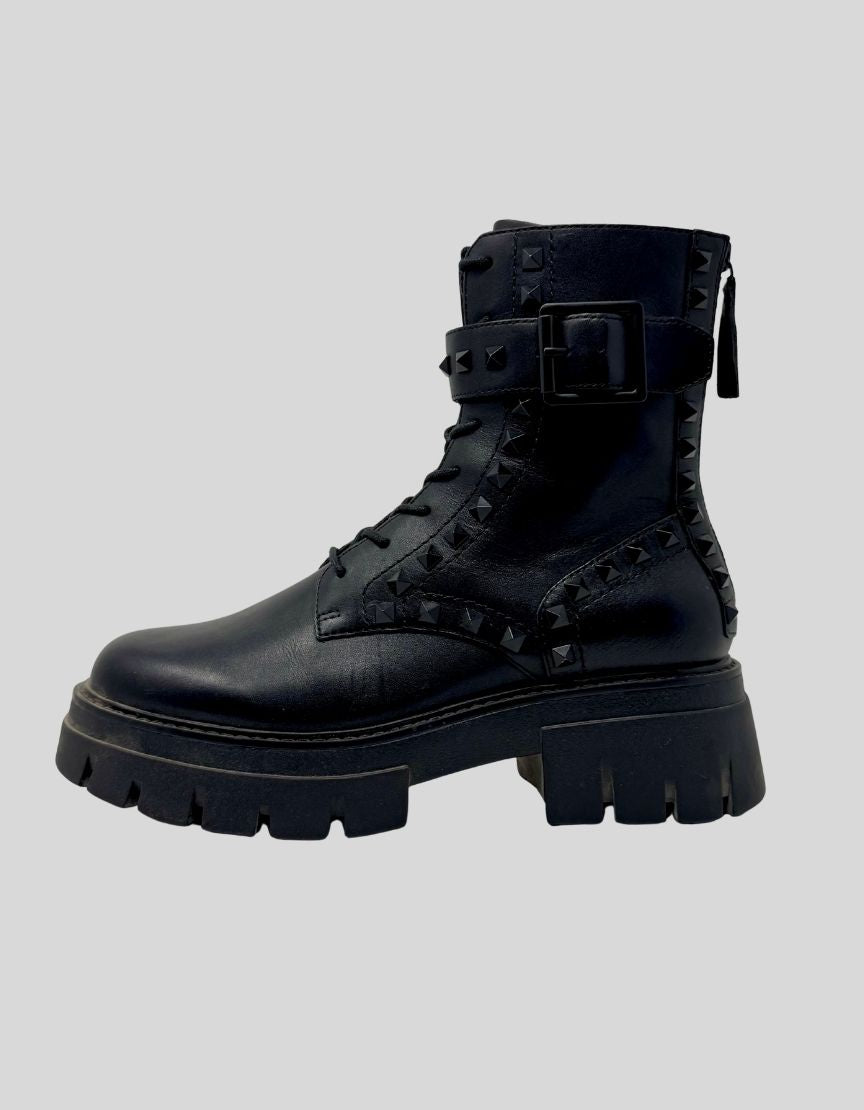 Authentic screen-worn ASH Lynch Studs combat boots in black leather. Features pyramid stud detailing throughout upper, dual zipper system with decorative front lacing and functional side zip. Chunky rubber lug sole with platform height.