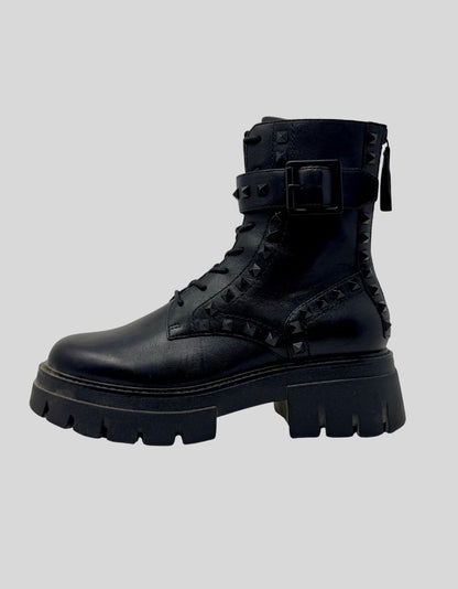Authentic screen-worn ASH Lynch Studs combat boots in black leather. Features pyramid stud detailing throughout upper, dual zipper system with decorative front lacing and functional side zip. Chunky rubber lug sole with platform height.