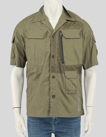 G-STAR RAW sage green utility overshirt featuring tactical-inspired design with mesh ventilation panels on chest and back. Multiple functional pockets include zippered chest pocket, button-flap cargo pockets, and internal storage. Short-sleeve