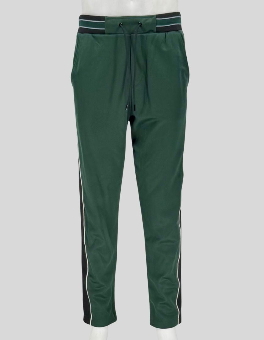 THE KOOPLES forest green track pants featuring contrast side stripes in black and white with piping detail. Elastic waistband, adjustable drawstring, side pockets, and tapered leg.
