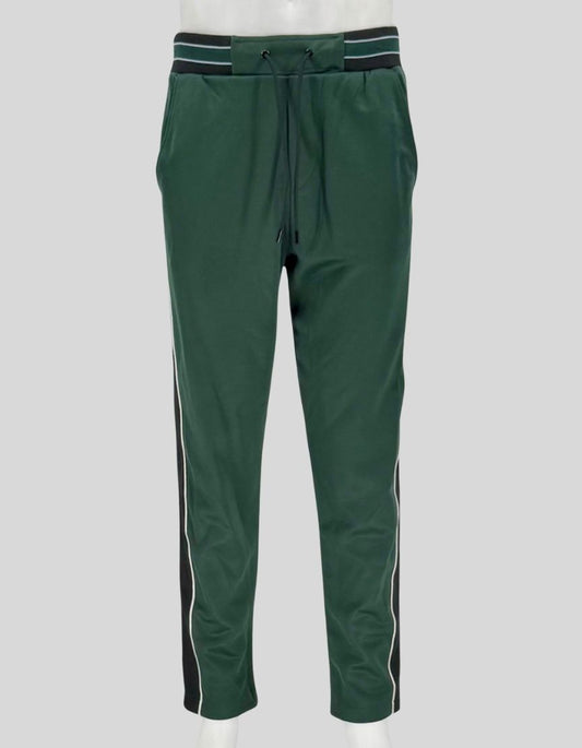 THE KOOPLES forest green track pants featuring contrast side stripes in black and white with piping detail. Elastic waistband, adjustable drawstring, side pockets, and tapered leg.
