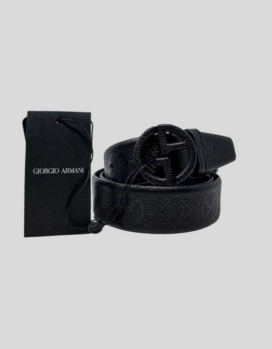 GIORGIO ARMANI belt in black pebbled calfskin leather featuring the iconic round GA logo buckle. The buckle is covered in matching black pebbled leather for a refined tonal effect, with the interlocking GA monogram cut-out revealing the metal beneath. Subtle embossed GA logos