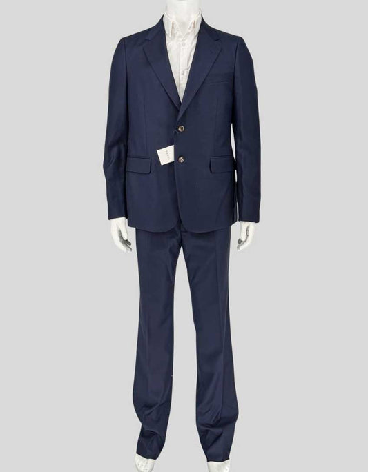 GUCCI wool suit in navy from the Italian luxury house known for exceptional tailoring and refined menswear. Single-breasted jacket features notched lapels, two-button closure, flap pockets, and burgundy satin lining.