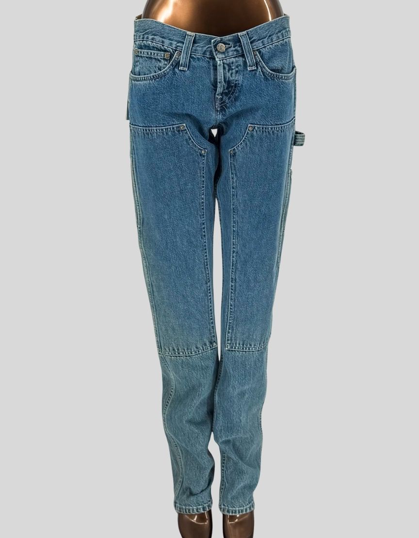 HELMUT LANG Masc Lo Utility jeans in "Accelerated High Contrast Indigo" wash. Workwear-inspired design with rivet-reinforced double panel chap front, utility pockets, and self-fabric hammer loop. Very low rise sits at the hip with a low "v" dip at top front. Slim straight leg through thigh and knee, cut long to stack at hem.