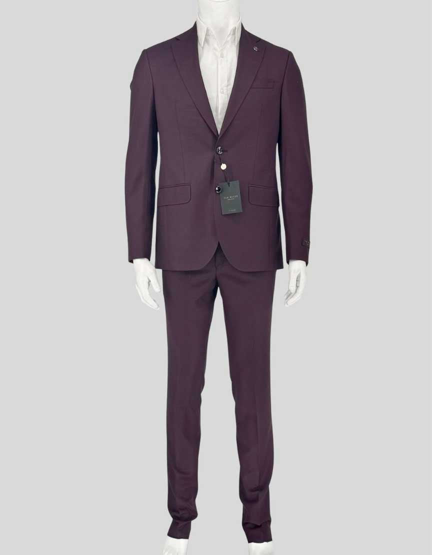 TED BAKER LONDON two-piece suit in rich burgundy featuring a modern slim fit. Canadian-made blazer with two-button closure, notched lapels, and flap pockets. The interior showcases a sophisticated geometric diamond pattern lining in navy and burgundy tones. Matching flat front trousers complete the suit.